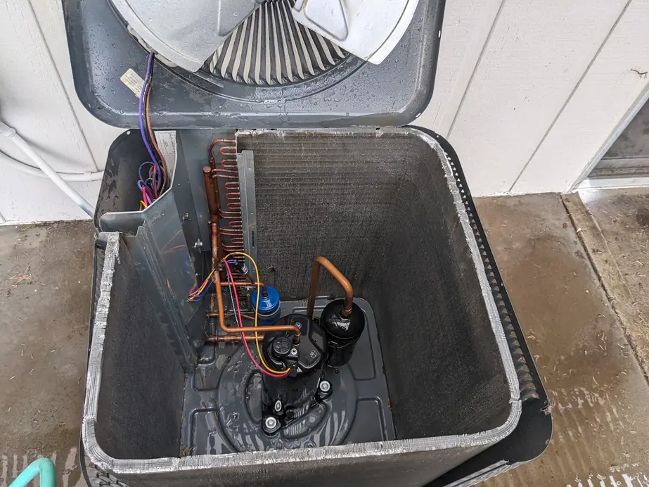 Opened condenser showing the compressor and wiring during an AC repair