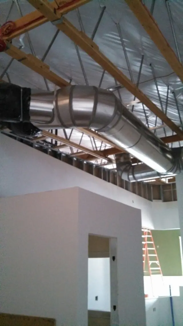 Commercial spiral duct run hung from open roof trusses